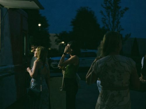 Mennesker samlet rundt en matvogn i skumringen, venter på servering fra et mobilt kjøkken.